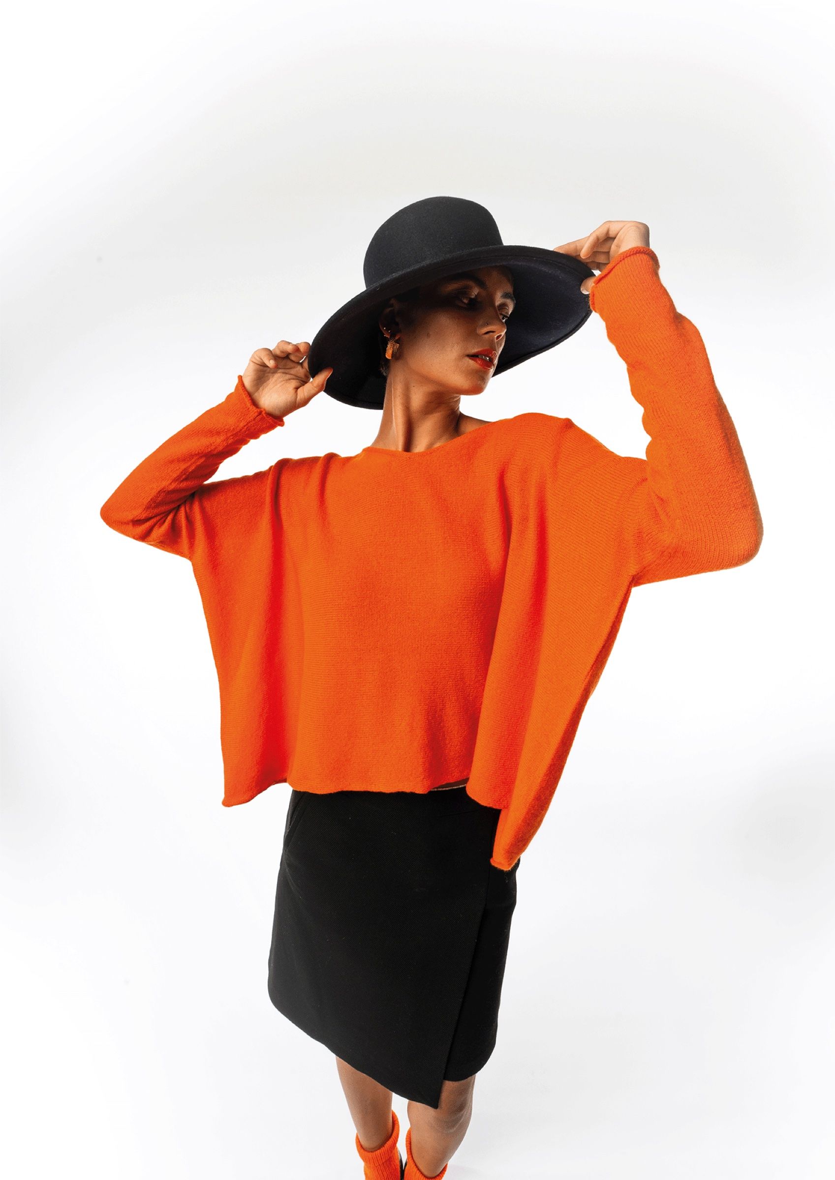 Model in orangem Oversize-Pullover und breitem Hut